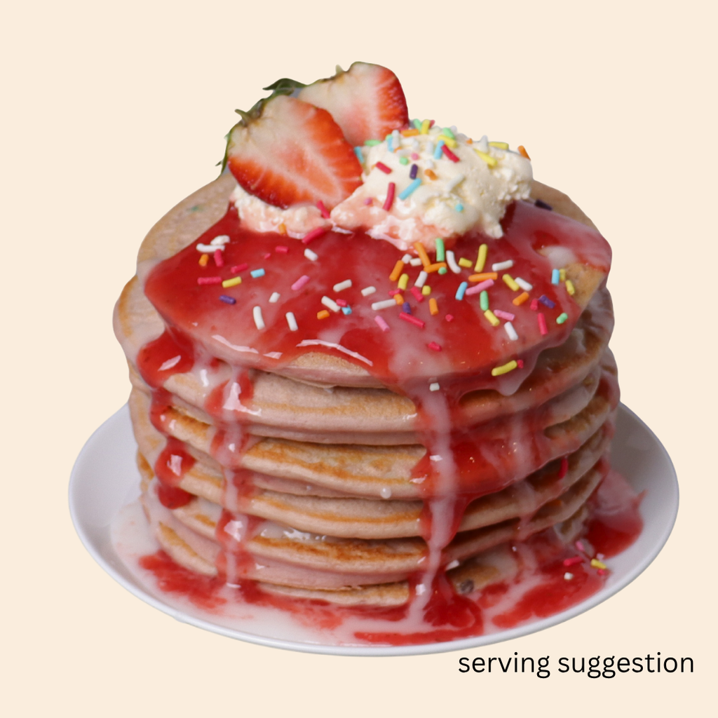Stack of Unicorn flavoured protein pancakes produced by SwoleCakes with strawberry sauce, whipped cream, and sprinkles as a serving suggestion.